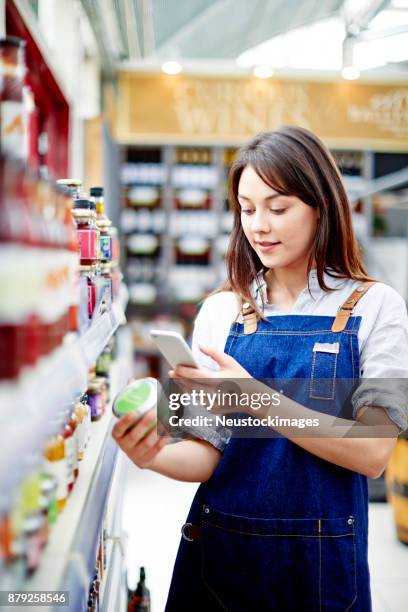 mooie deli eigenaar scannen etiket op de verpakking van het voedsel - conagra general mills brand products on the shelf ahead of earns stockfoto's en -beelden