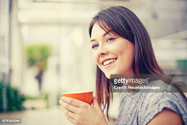 seitenansicht der glückliche frau hält die kaffeetasse im café - neustockimages stock-fotos und bilder