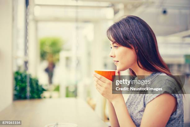 seitenansicht der nachdenkliche frau mit kaffeetasse im café - neustockimages stock-fotos und bilder