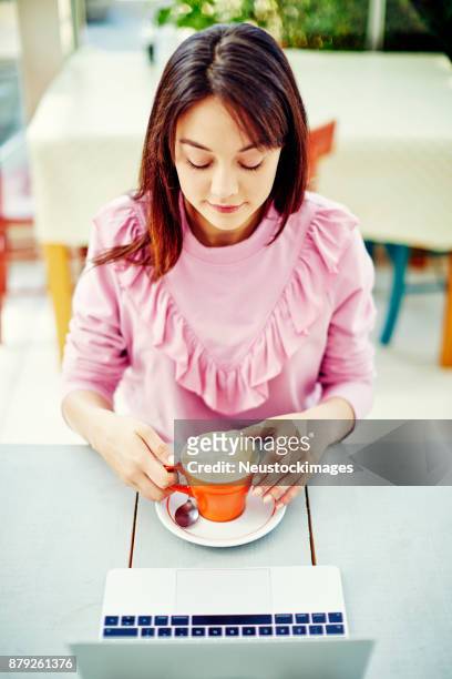 schöne frau mit laptop am tisch im café kaffeetrinken - neustockimages stock-fotos und bilder