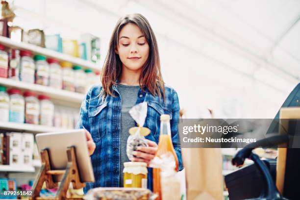 schöne deli inhaber halten lebensmittelpaket bei der verwendung von digitalen tisch - neustockimages stock-fotos und bilder