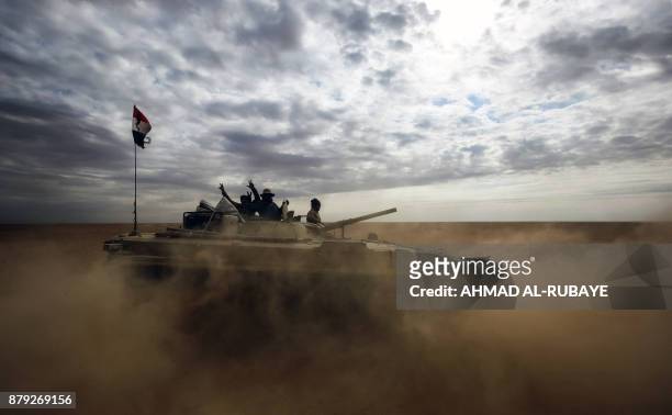 Iraqi fighters flash the victory gesture from an advancing armoured personnel carrier as the Iraqi forces, supported by members of the Hashed...