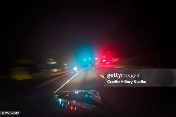car driving down road with red and blue lights - police lights fotografías e imágenes de stock