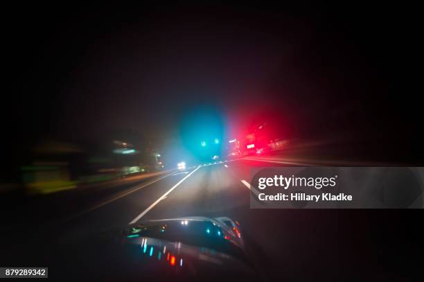 car driving down road with red and blue lights - cop car photos et images de collection