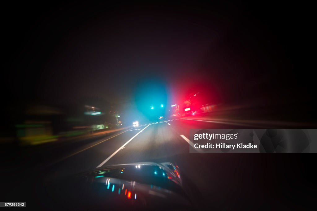 Car driving down road with red and blue lights