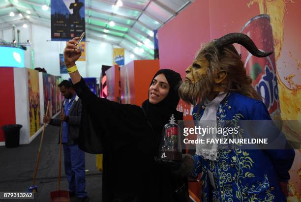 Saudi woman uses her cell phone to take a "selfie" photograph with a cosplayer dressed as the Beast from Disney's 2017 live-action "Beauty and the...