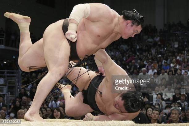Yokozuna-ranked sumo wrestler Hakuho of Mongolia throws Goeido of Japan during their bout on the final day of the 15-day Kyushu Grand Sumo Tournament...