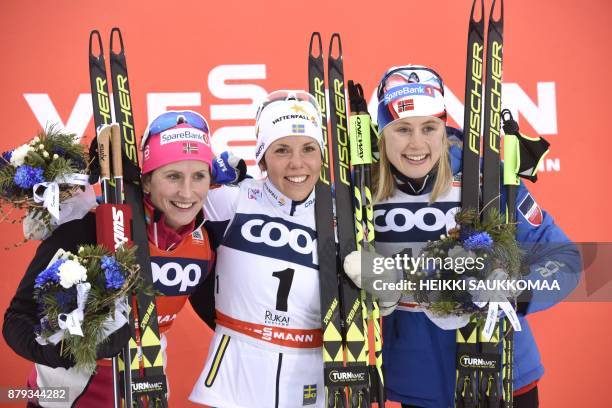 Second placed Marit Bjoergen of Norway, winner Charlotte Kalla of Sweden and third placed Ragnhild Haga of Norway pose on the podium after the...