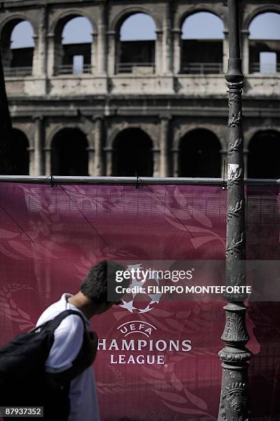 Visitor walks by a UEFA Champions League soccer logo in front of the ancient Colosseum at the Champions Village in Rome's Colle Oppio on May 23,...