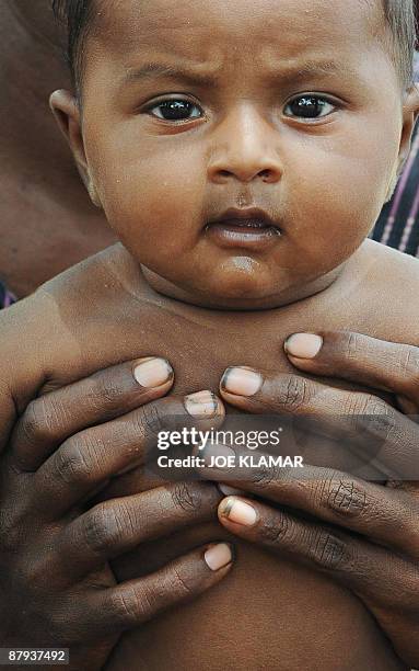 An internally displaced Sri Lankan mother holds up her infant during a visit by United Nations Secretary-General Ban Ki-moon at Menik Farm refugee...