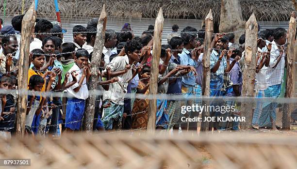 Internally displaced Sri Lankan people wait behind a fence during a visit by United Nations Secretary-General Ban Ki-moon at Menik Farm refugee camp...