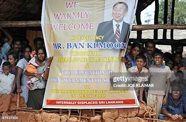 Internally displaced Sri Lankan people wait behind a welcome banner during a visit by United Nations Secretary-General Ban Ki-moon at Menik Farm...