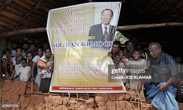 Internally displaced Sri Lankan people wait behind a welcome banner for a visit by United Nations Secretary-General Ban Ki-moon at Menik Farm refugee...