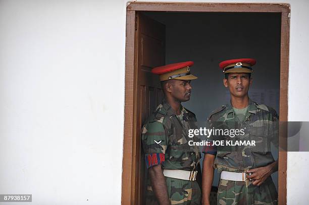Sri Lankan Military Policemen look on from a doorway during United Nations Secretary-General Ban Ki-moon's visit to Menik Farm refugee camp in...