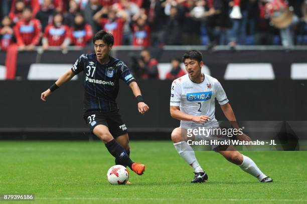 Akito Takagi of Gamba Osaka controls the ball under pressure of Tomonobu Yokoyama of Consadole Sapporo during the J.League J1 match between Gamba...