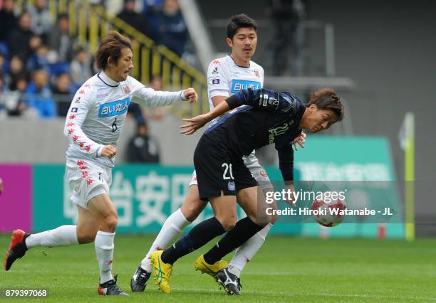 Shun Nagasawa of Gamba Osaka controls the ball under pressure of Shingo Hyodo and Tomonobu Yokoyama of Consadole Sapporo during the J.League J1 match...