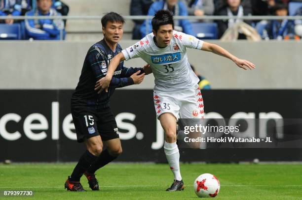 Ryosuke Shindo of Consadole Sapporo and Yasuyuki Konno of Gamba Osaka compete for the ball during the J.League J1 match between Gamba Osaka and...