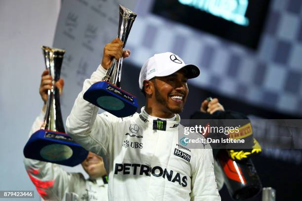 Second place finisher Lewis Hamilton of Great Britain and Mercedes GP celebrates with his trophy on the podium during the Abu Dhabi Formula One Grand...