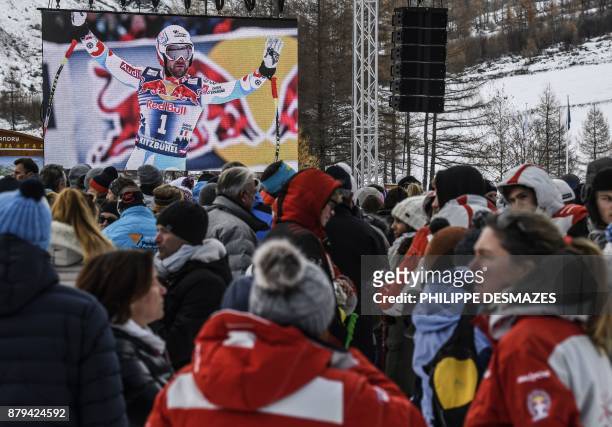 Screen shows a photo of late French skier David Poisson as people attend a ceremony in his memory in Peisey-Nancroix, in the French Alps, on November...