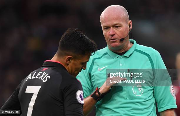 Referee Lee Mason interacts with Arsenal's Chilean striker Alexis Sanchez during the English Premier League football match between Burnley and...