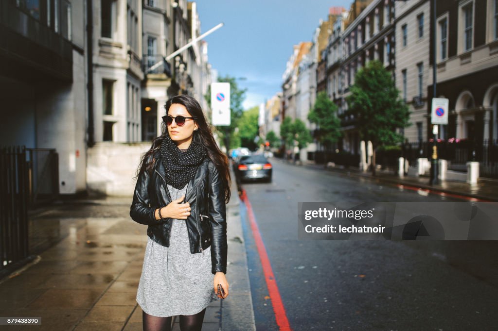 Giovane donna che cammina a Londra, quartiere Di Soho, sms al telefono