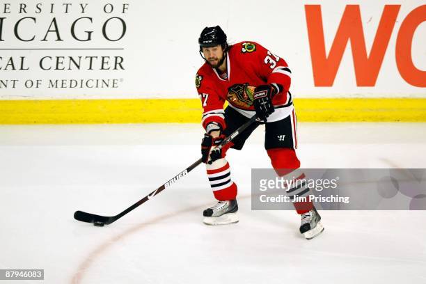 Adam Burish of the Chicago Blackhawks controls the puck against the Detroit Red Wings during Game Three of the Western Conference Championship Round...