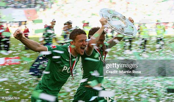 Sascha Riether and Christian Gentner of Wolfsburg celebrate the German championship with the trophy after their Bundesliga match against SV Werder...