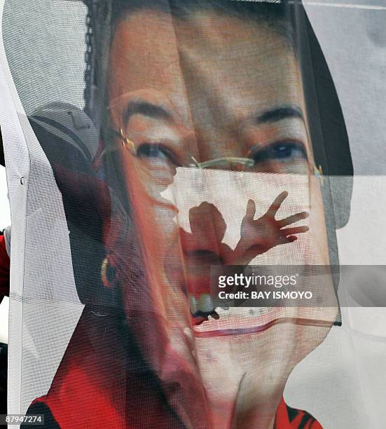 Supporter of former Indonesian president Megawati Sukarnoputri, the head of the Indonesia Democratic Party of Struggle, is silhouetted through a...