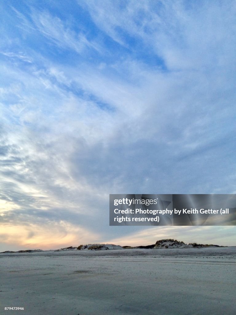 A cloud formation rising above sand dunes