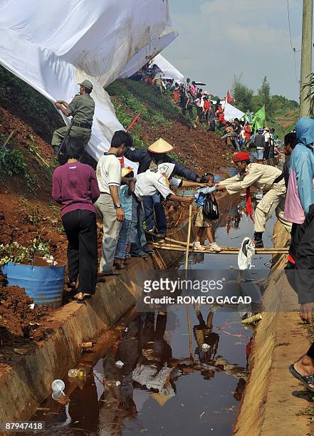 Supporters cross a canal of waste sludge at a rubbish dump in Bantar Gebang on May 24, 2009 to attend the presidential declaration of former...