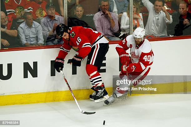 Andrew Ladd of the Chicago Blackhawks attempts to control the puck against Henrik Zetterberg of the Detroit Red Wings during Game Three of the...