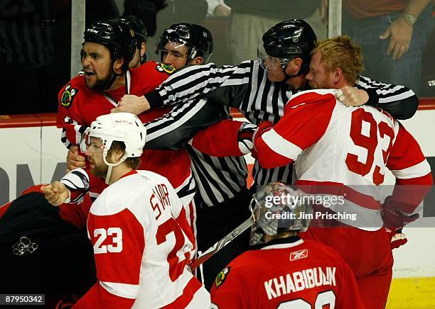 Dustin Byfuglien of the Chicago Blackhawks is restrained as he yells at Niklas Kronwall of the Detroit Red Wings after Kronwall delievered a hard...