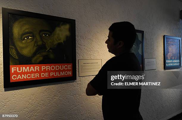 By Juan Jose Rodriguez A man observes a picture of former Cuban President Fidel Castro smoking with the message ''Smoke produces lung cancer'' during...