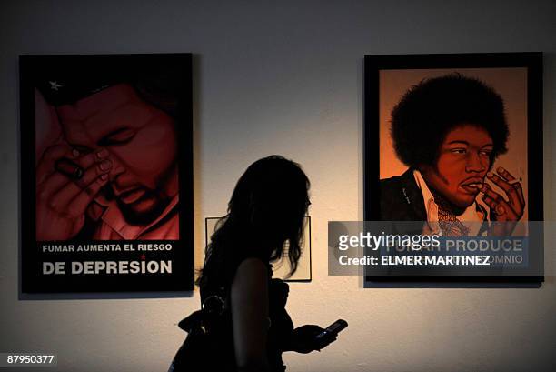 By Juan Jose Rodriguez A woman looks at pictures of revolutionary leader Ernesto Che Guevara and musician Jimmy Hendrix smoking with the messages...