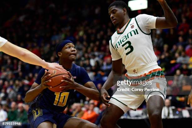 Isiah Deas of the La Salle Explorers drives against Anthony Lawrence II of the Miami Hurricanes during the first half at Santander Arena on November...