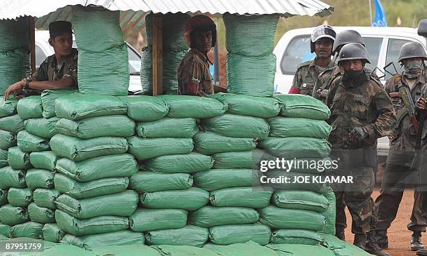 Sri Lankan soldiers stand guard during United Nations Secretary-General Ban Ki-moon's visit to Menik Farm refugee camp in Cheddikulam on May 23,...