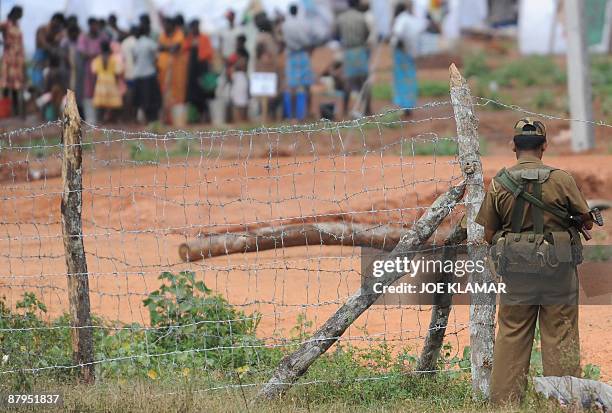 Sri Lankan soldier stands guard during United Nations Secretary-General Ban Ki-moon's visit to Menik Farm refugee camp in Cheddikulam on May 23,...