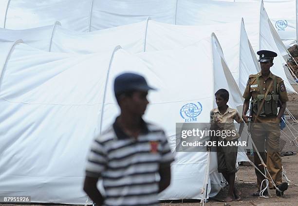 Sri Lankan soldier patrols between tents during a visit by United Nations Secretary-General Ban Ki-moon at Menik Farm refugee camp in Cheddikulam on...