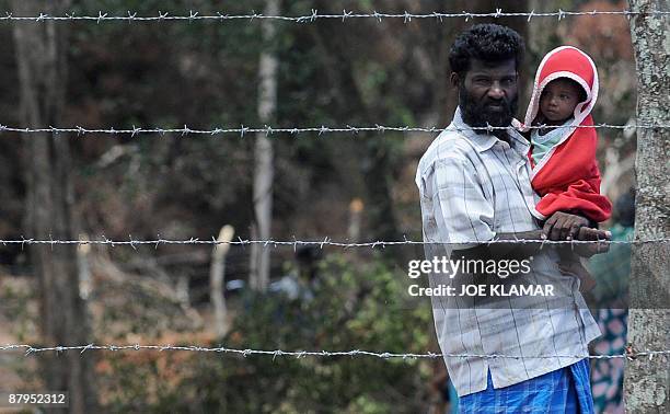 Internally displaced Sri Lankan people stand behind barbed wire during a visit by United Nations Secretary-General Ban Ki-moon at Menik Farm refugee...