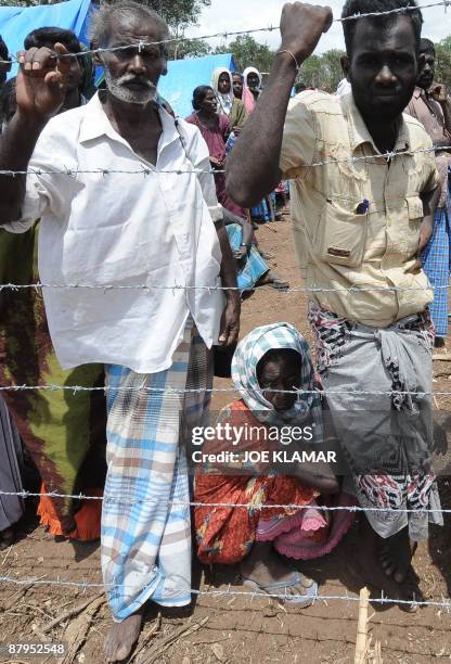 Internally displaced Sri Lankan people stand behind barbed wire between tents during a visit by United Nations Secretary-General Ban Ki-moon at Menik...