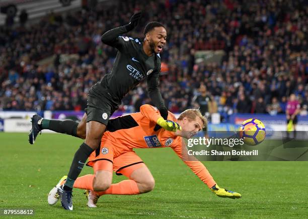 Raheem Sterling of Manchester City and Jonas Lossl of Huddersfield Town clash during the Premier League match between Huddersfield Town and...