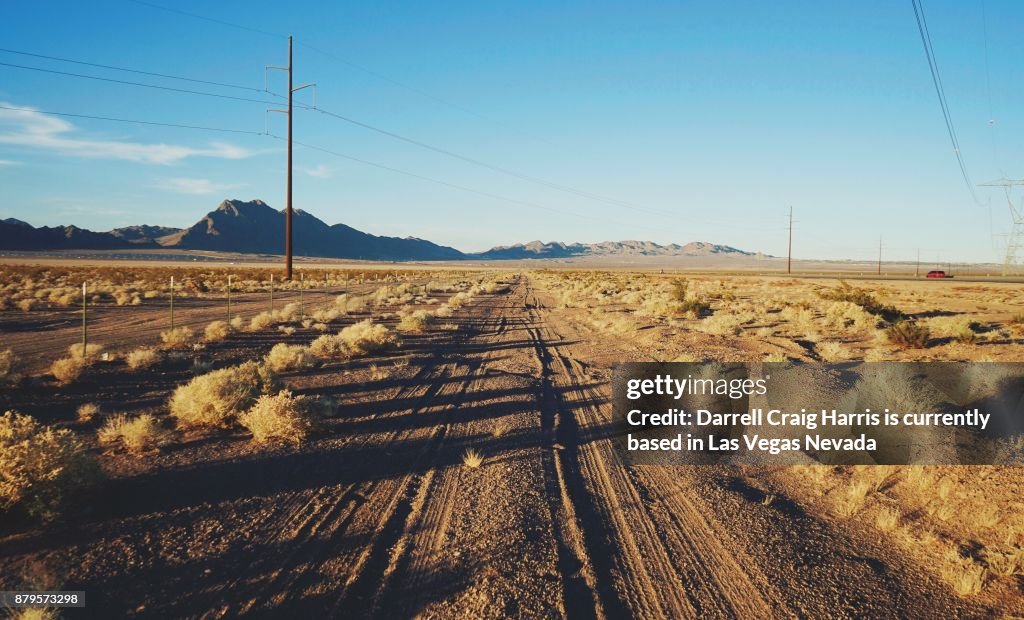 Nevada desert road with power lines and poles in the background late afternoon