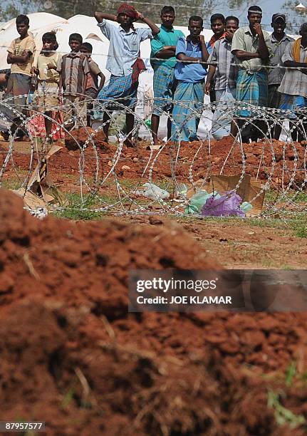 Internally displaced Sri Lankan people wait behind barbed wire during a visit by United Nations Secretary-General Ban Ki-moon at Menik Farm refugee...