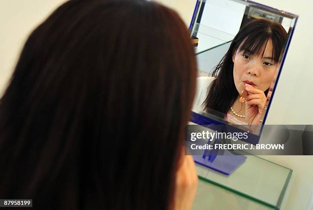 Customer looks into a mirror while sampling an electronic cigarette at a shop in Beiijng on May 25, 2009. Also known as an 'e-cigarette', the...