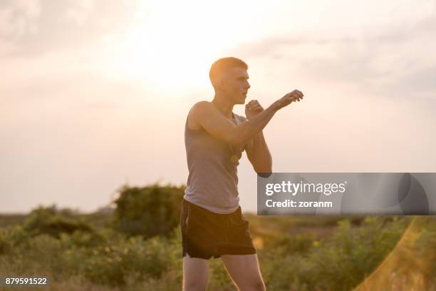 man trainging shadow boxing outdoors - tai chi shadow stock pictures, royalty-free photos & images