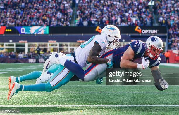 Rob Gronkowski of the New England Patriots catches a touchdown pass as he is defended by Reshad Jones of the Miami Dolphins during the first quarter...