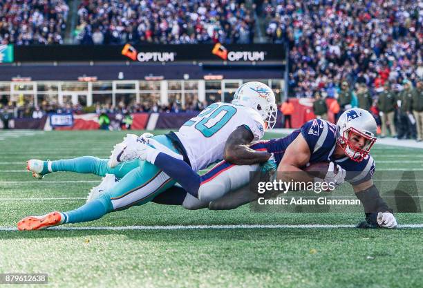 Rob Gronkowski of the New England Patriots catches a touchdown pass as he is defended by Reshad Jones of the Miami Dolphins during the first quarter...