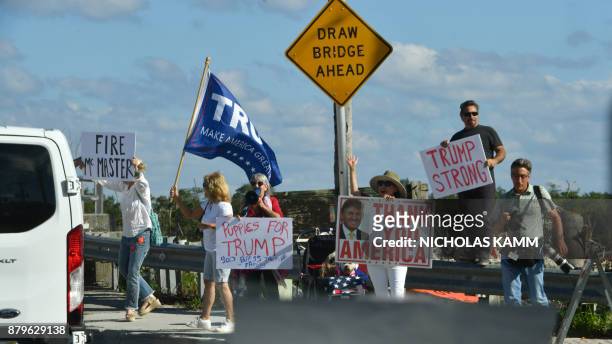 Pro and Anti supporters of US President Donald Trump wave as the Presidential motorcade passes by in Mar-a-Lago, Florida on November 26, 2017....