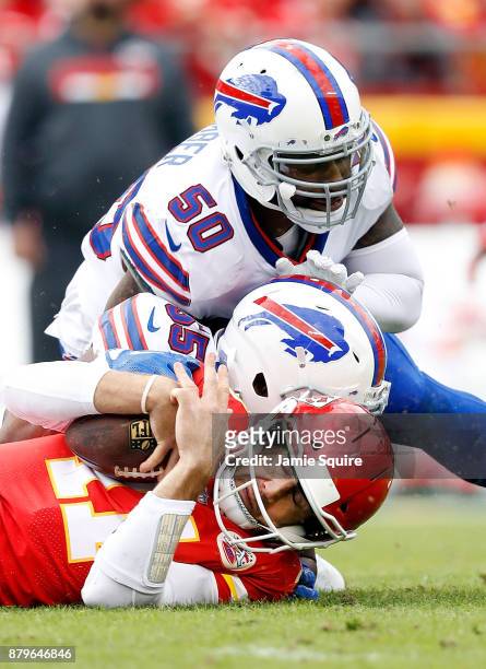 Quarterback Alex Smith of the Kansas City Chiefs is tackled by Jerry Hughes and outside linebacker Ramon Humber of the Buffalo Bills after scrambling...