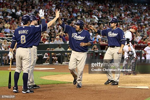 Chris Burke of the San Diego Padres congratulates teammates Kevin Kouzmanoff, Henry Blanco and Adrian Gonzalez after they scored against the Arizona...